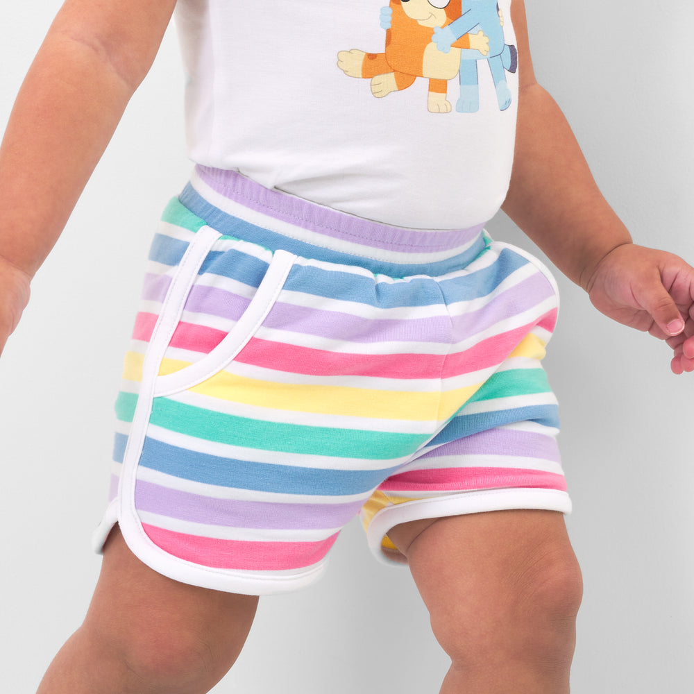 Close up image of a child wearing Rainbow Stripes dolphin shorts and coordinating top