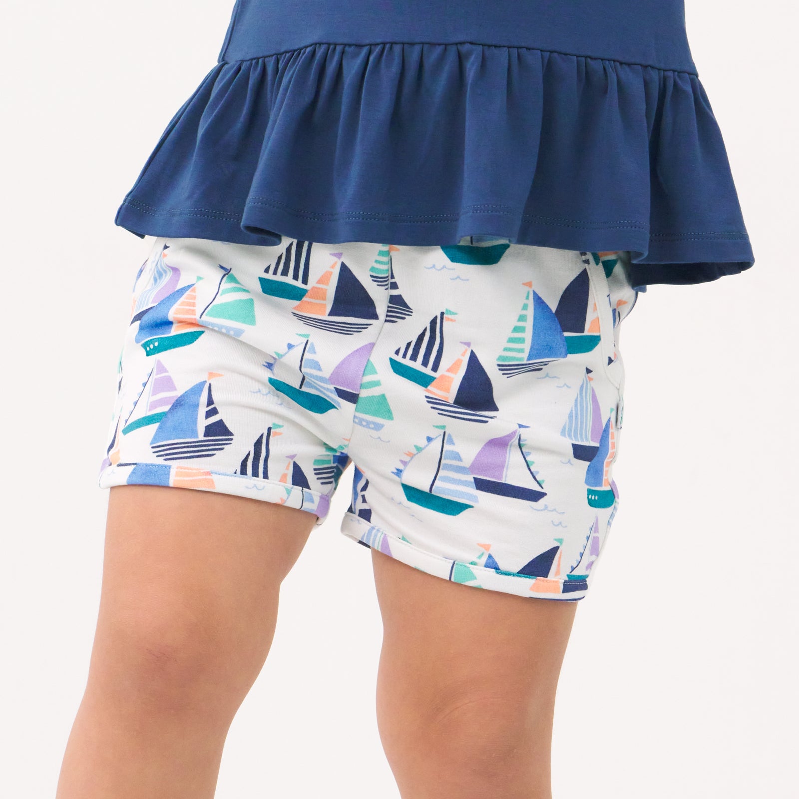Close up image of a child wearing Seas the Day dolphin shorts