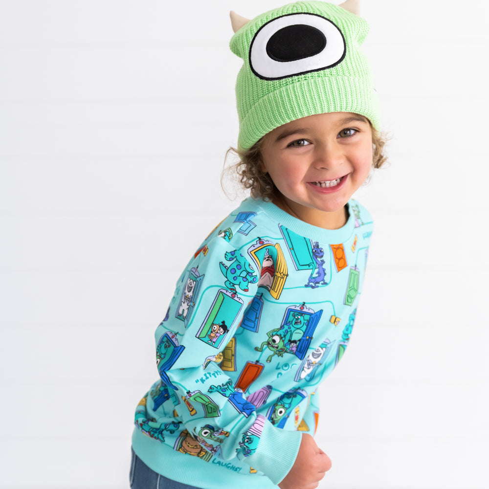 Smiling child wearing the Disney Monsters, Inc. Mike Wazowski Beanie Hat and Disney Monsters, Inc. Scream Team Crewneck Sweatshirt