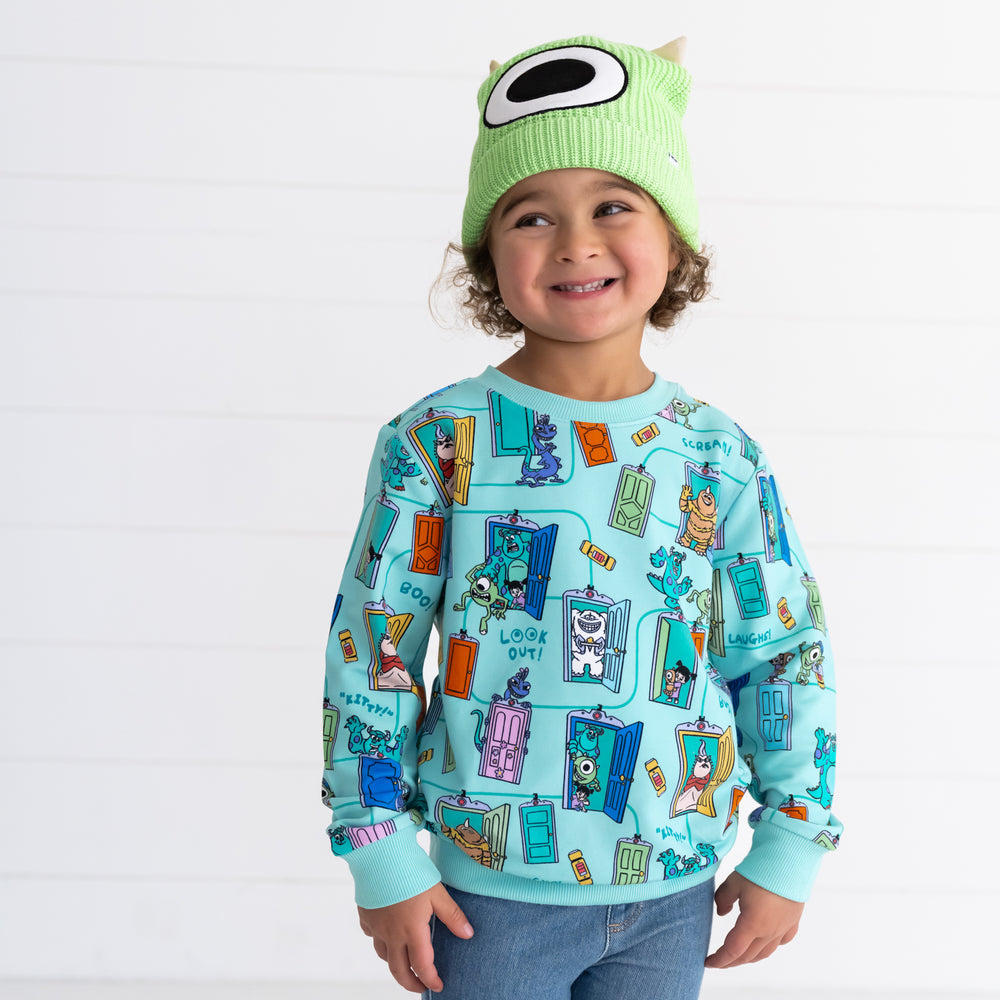 Additional image of smiling child wearing the Disney Monsters, Inc. Mike Wazowski Beanie Hat and Disney Monsters, Inc. Scream Team Crewneck Sweatshirt