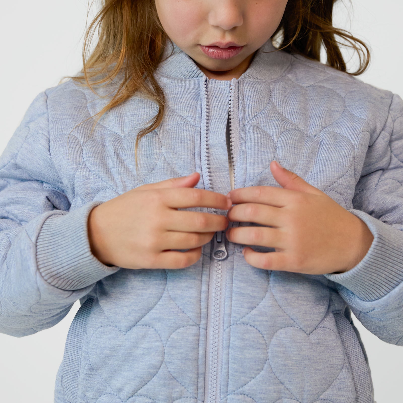 Close up of a child zipping up a Light Blue Denim Quilted Varsity Jacket