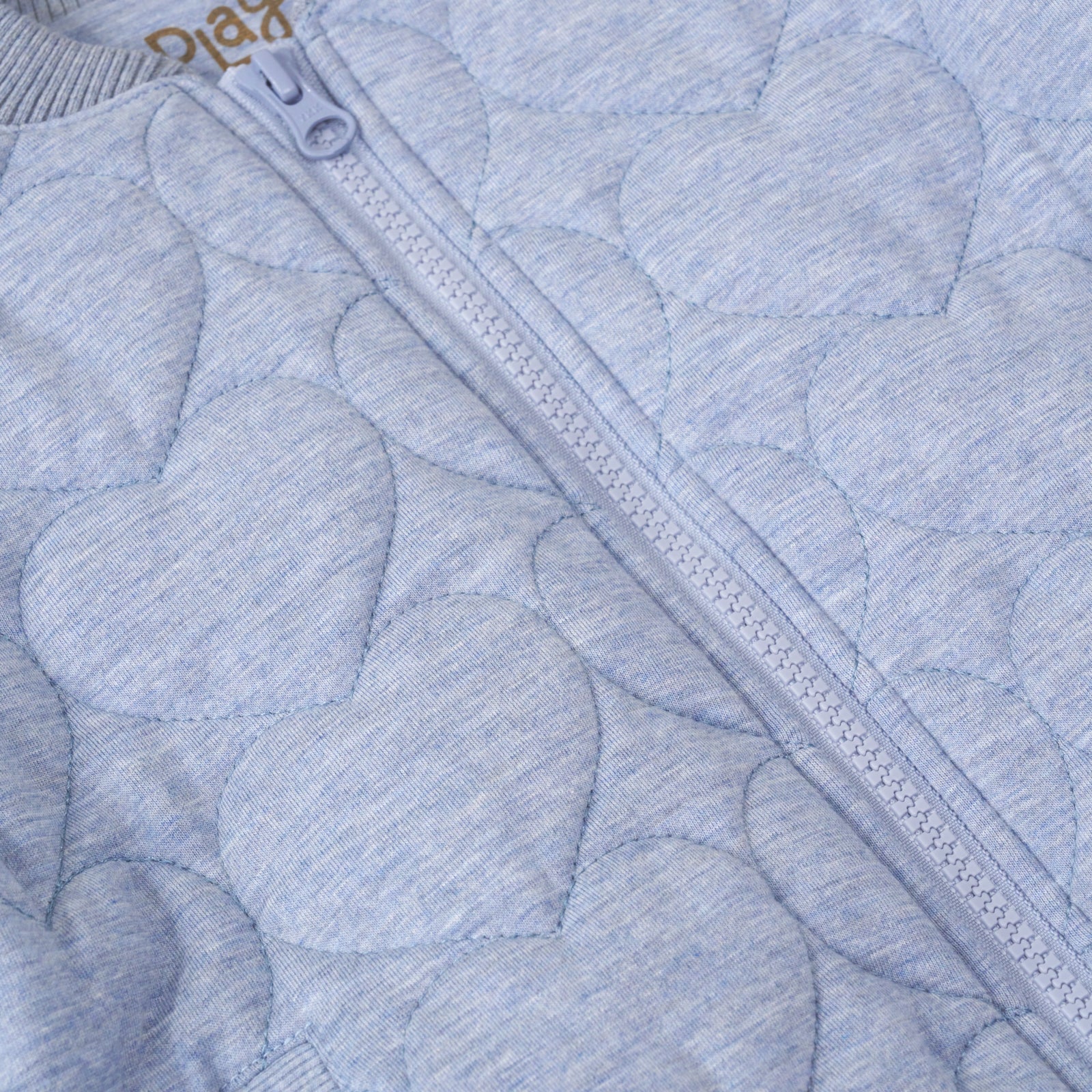 close up view of the zipper on a light blue denim quilted varsity jacket