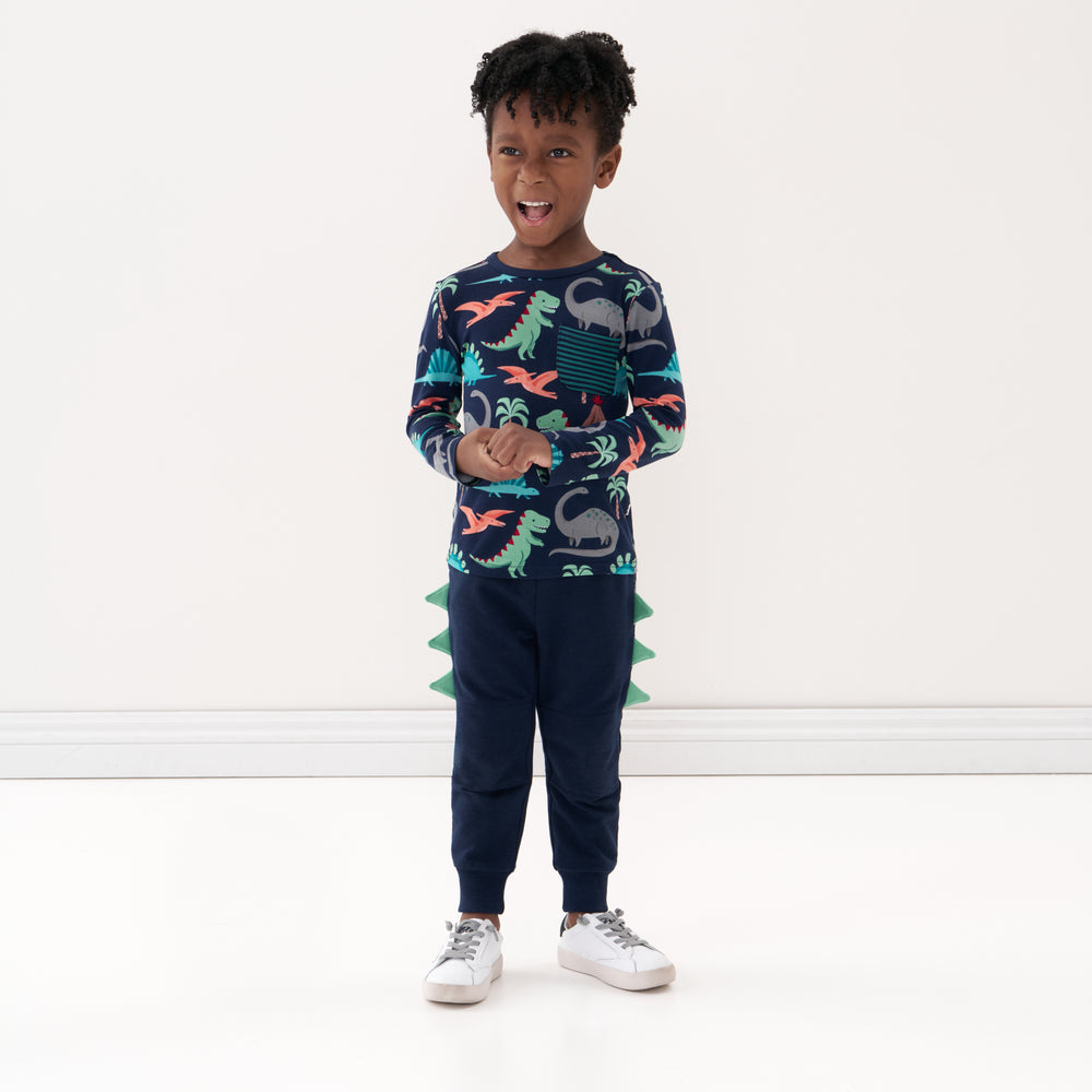 Click to see full screen - Child holding their hands together wearing Dinosaur joggers and coordinating pocket tee