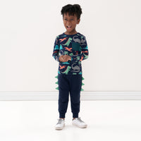 Child holding their hands together wearing Dinosaur joggers and coordinating pocket tee