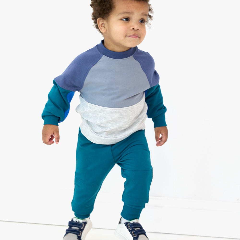 Image of child walking while in the Glacier Blue Jogger and Windy Sky Panel Crewneck