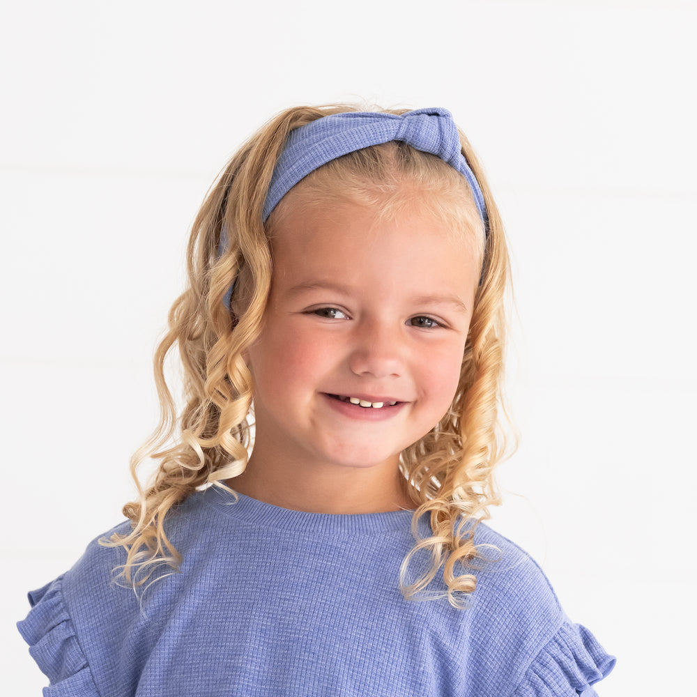 Close up image of a child wearing a Heather Lilac Knotted Headed and Flutter Crewneck