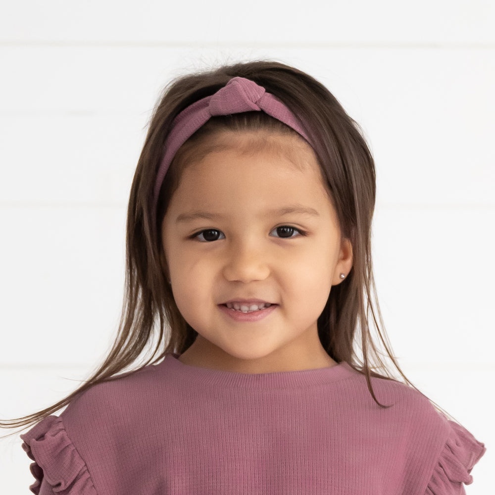 Close up image of a child wearing a Dusty Plum Waffle Knotted Headband and matching Flutter Crewneck