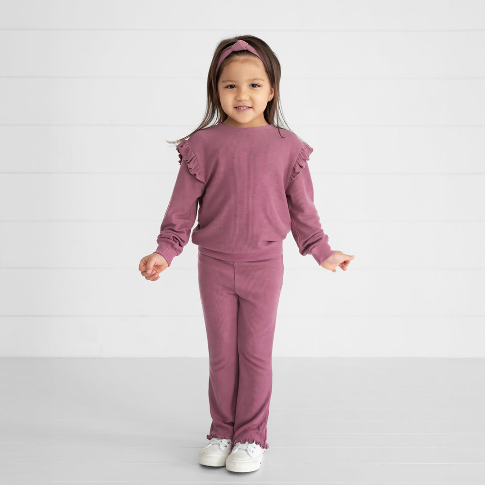 Image of a child wearing a Dusty Plum Waffle Flare Pant, Flutter Crewneck, and Knotted Headband