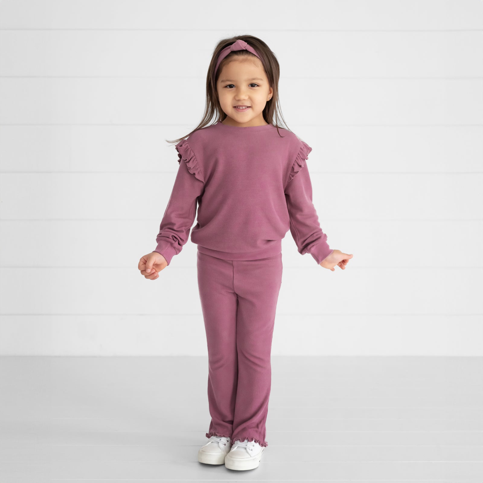 Image of a child wearing a Dusty Plum Waffle Flare Pant, Flutter Crewneck, and Knotted Headband