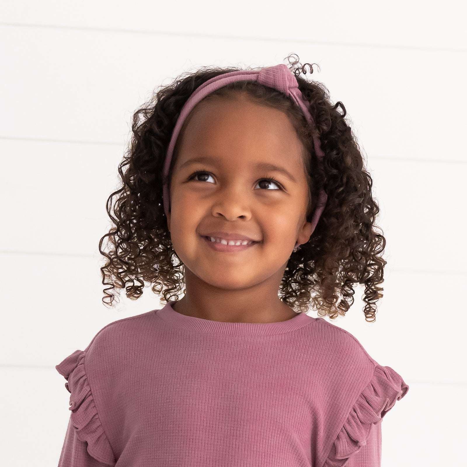 Alternate close up image of a child wearing a Dusty Plum Waffle Knotted Headband and matching Flutter Crewneck