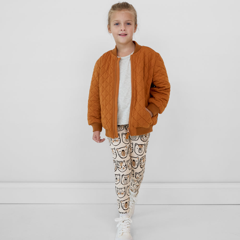 Child walking wearing Lions, Tigers & Bears leggings paired with a gray top and golden brown quilted varsity jacket