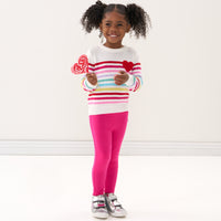 Child wearing Pink Punch leggings and a coordinating knit sweater