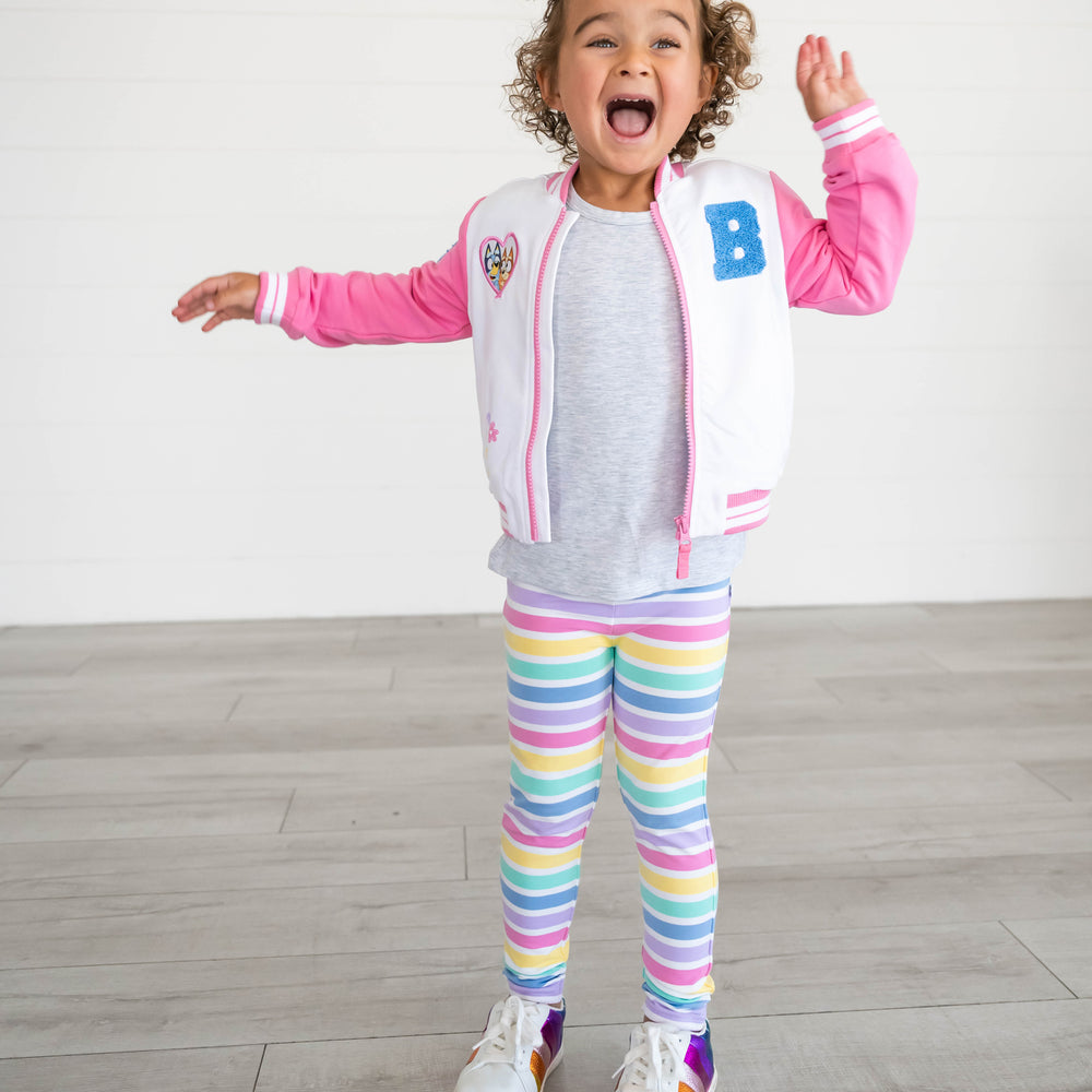 Girl smiling while wearing the Rainbow Stripes Legging and Bluey Pink Bomber Jacket
