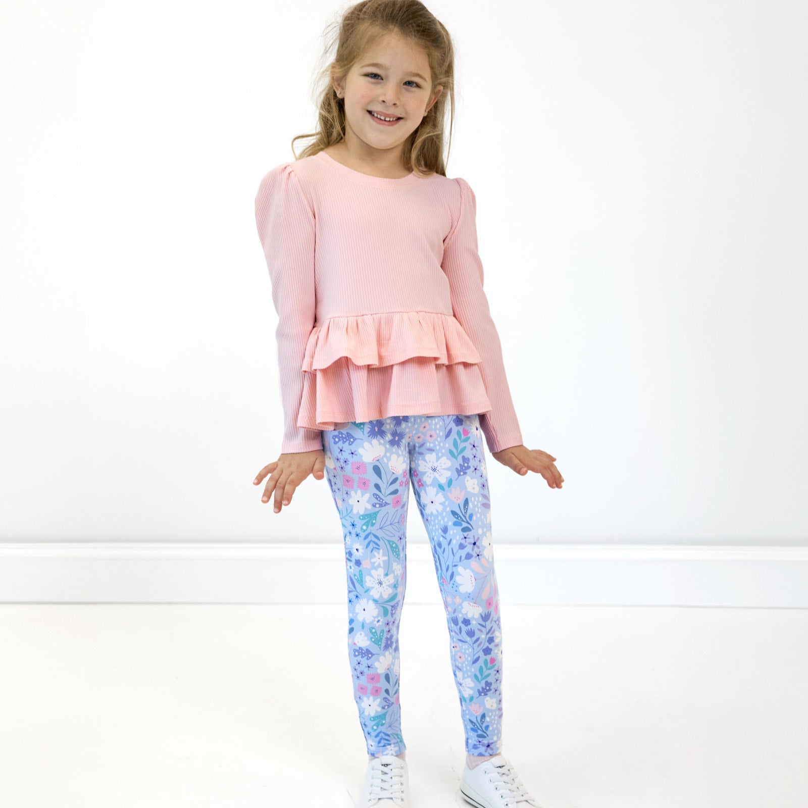 Girl posing while wearing the Magical Meadow Legging and Prima Pink Ribbed Tiered Peplum Top