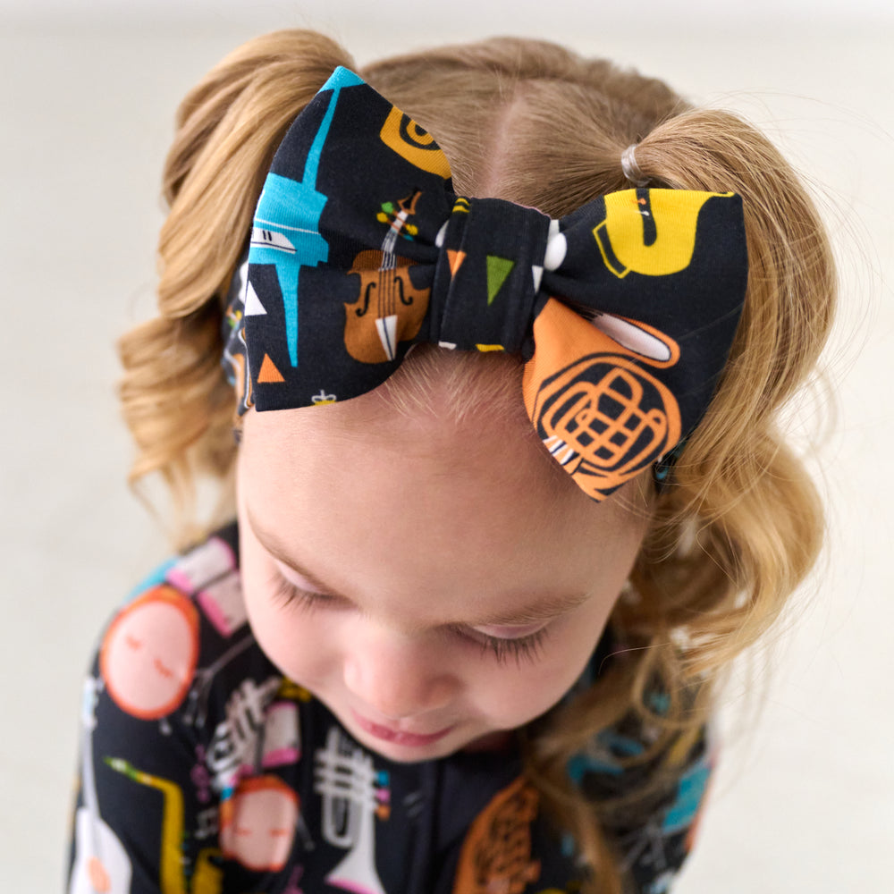 Close up image of a child wearing a Keys and Chords luxe bow headband and matching pajamas
