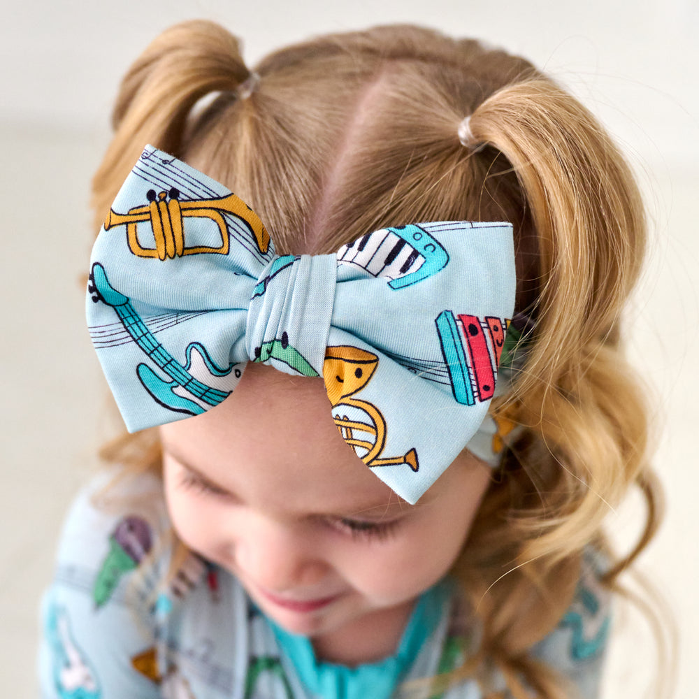 Close up image of a child wearing a Play Along luxe bow headband and matching pajamas