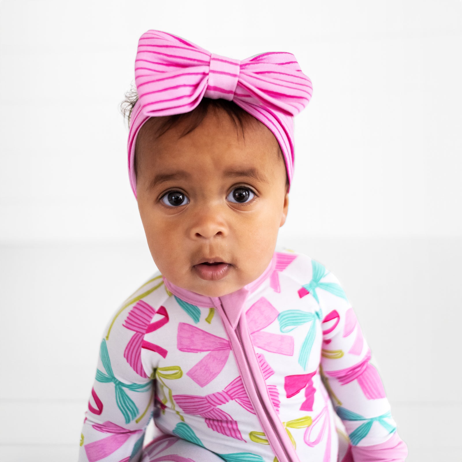 Close up image of a child wearing a Tonal Pink Stripes luxe bow headband