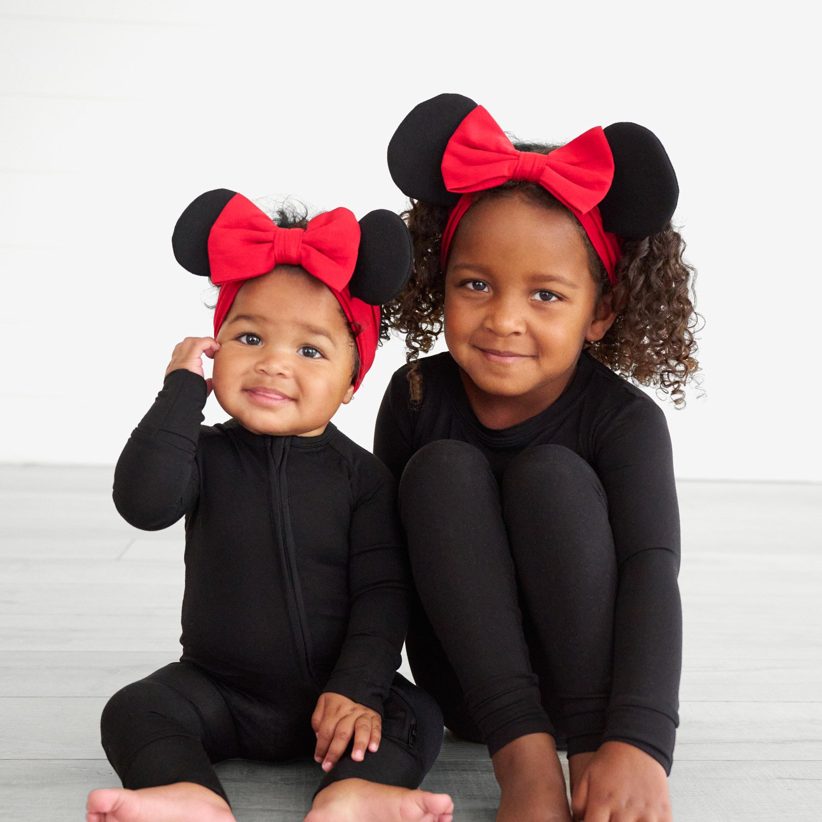 Two children sitting together wearing Minnie Mouse Ear Luxe bow Headbands