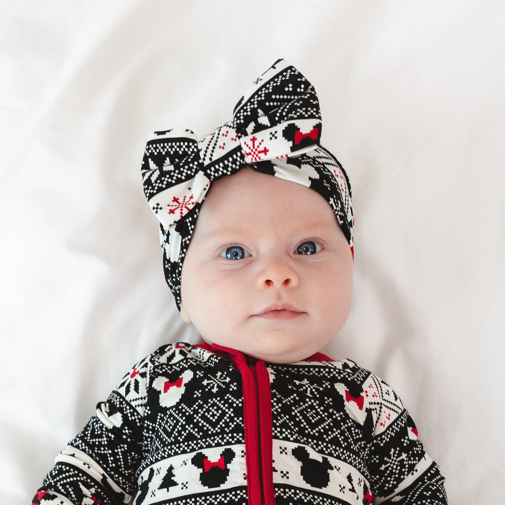 Child laying on a bed wearing a Mickey Fair Isle luxe bow headband.