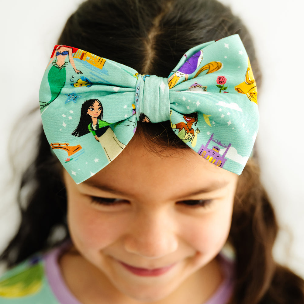 Click to see full screen - Close up image of a child wearing a Disney Princess Dreams luxe bow headband