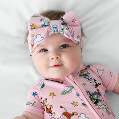 Image of a child laying on a bed wearing a Pink Toy Story Stars luxe bow headband