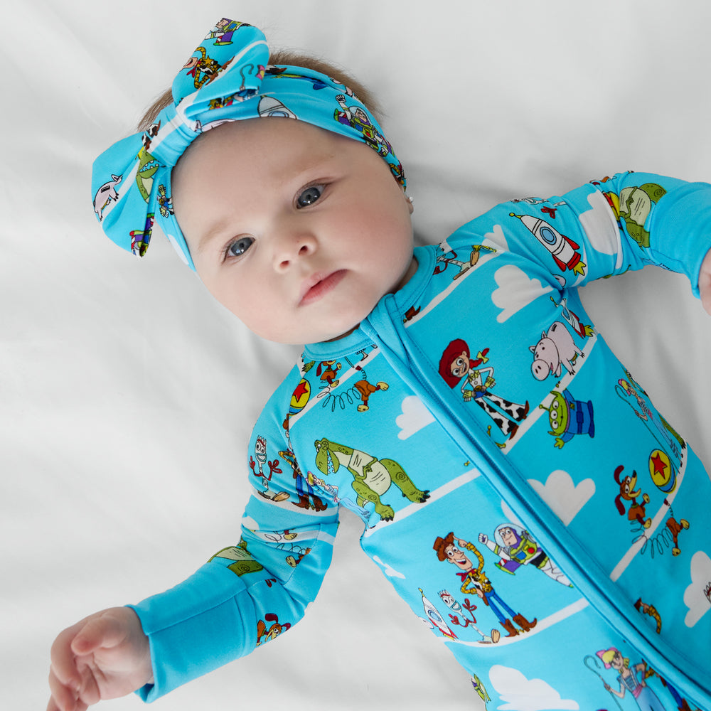 image of a child laying on a blanket wearing a Disney Pixar Toy Story Pals luxe bow headband and matching zippy