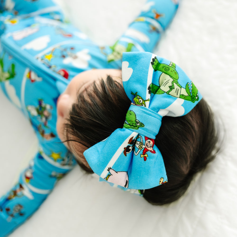 Child laying on a blanket wearing a Disney Pixar Toy Story Pals luxe bow headband and matching zippy