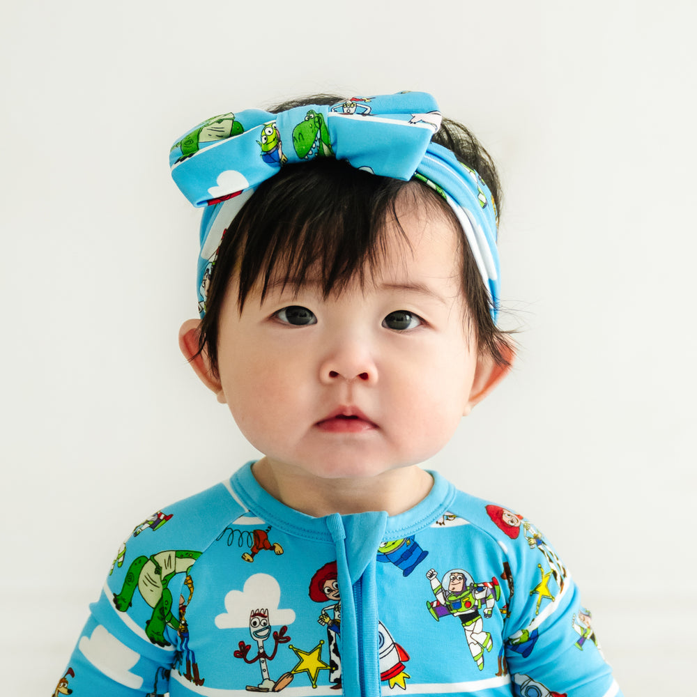 Close up image of a child wearing a Disney Pixar Toy Story Pals luxe bow headband and matching zippy