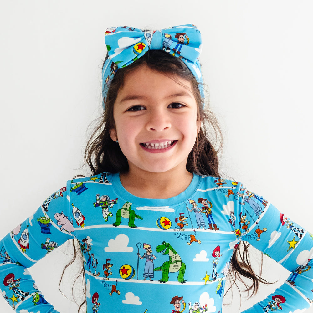 Image of a child wearing a two piece Toy Story Pals pj set and matching luxe bow headband