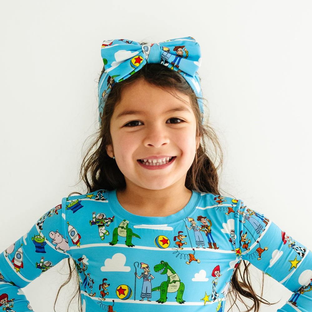 Child wearing a Disney Pixar Toy Story Pals luxe bow headband and matching pajamas