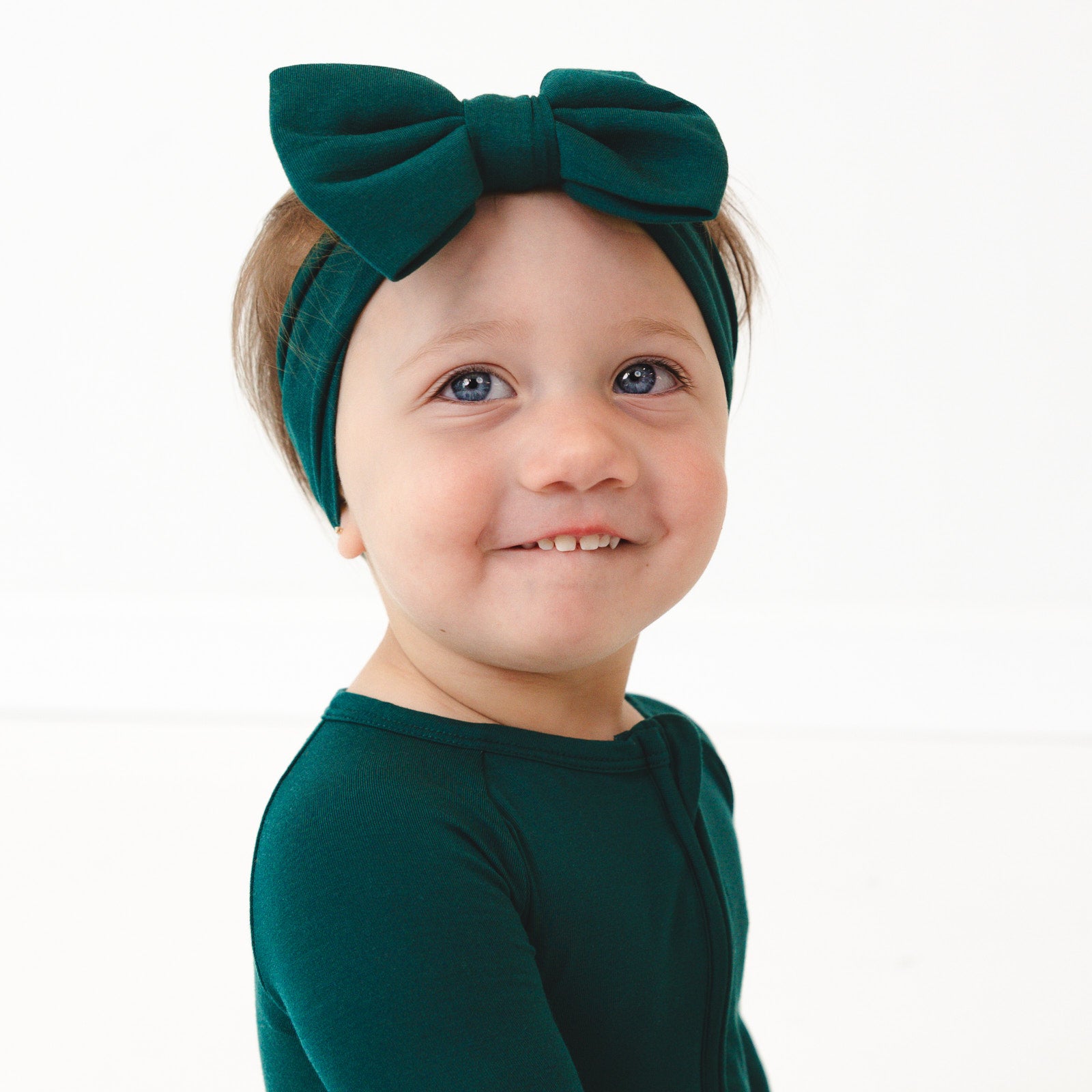 Alternate close up image of a child wearing the Emerald Luxe Bow Headband