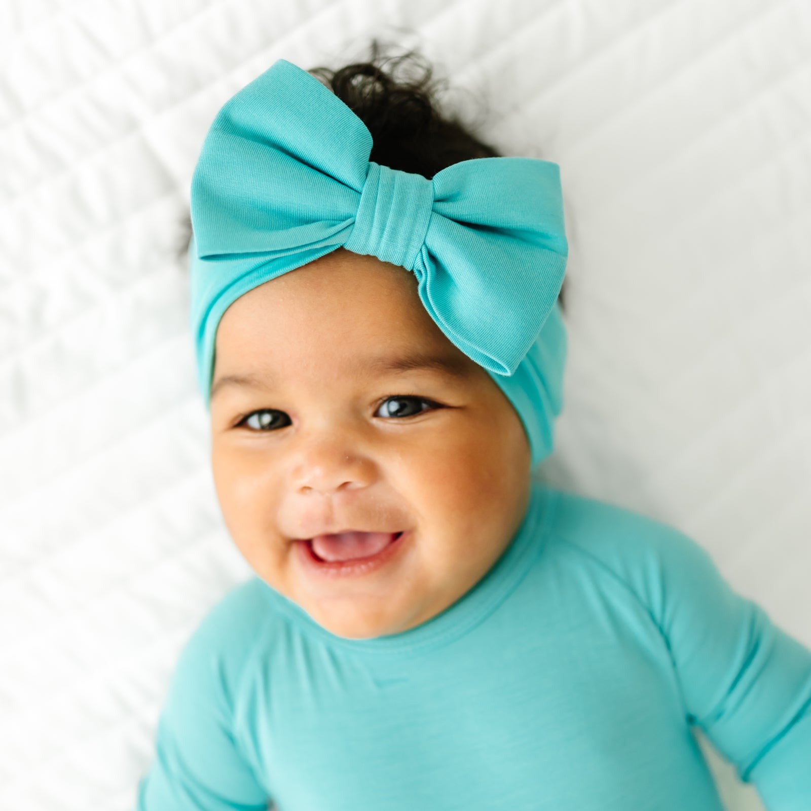 Close up image of a child wearing Glacier Turquoise luxe bow headband