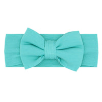 Flat lay image of a Glacier Turquoise luxe bow headband 