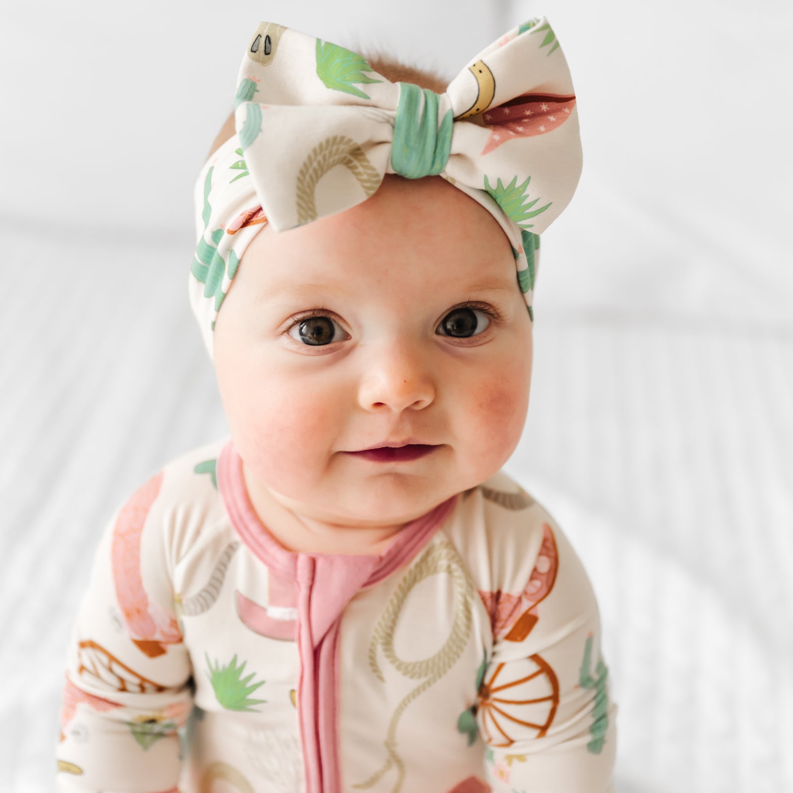 Close up image of a child wearing a Pink Ready to Rodeo luxe bow headband paired with a matching zippy