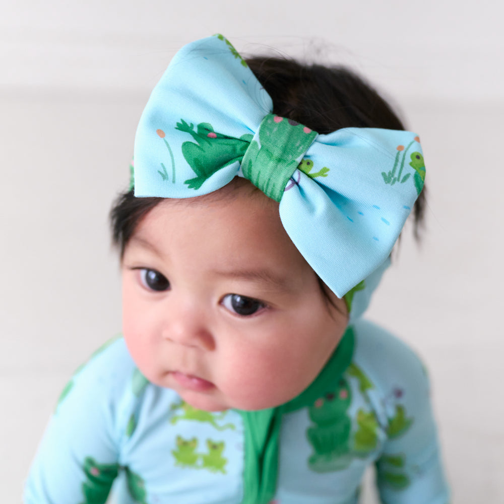 Close up image of a child wearing a Leaping Love luxe bow headband and matching zippy