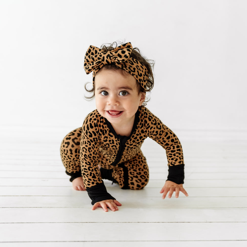 Girl crawling while wearing the Classic Leopard Luxe Bow Headband and Classic Leopard Zippy