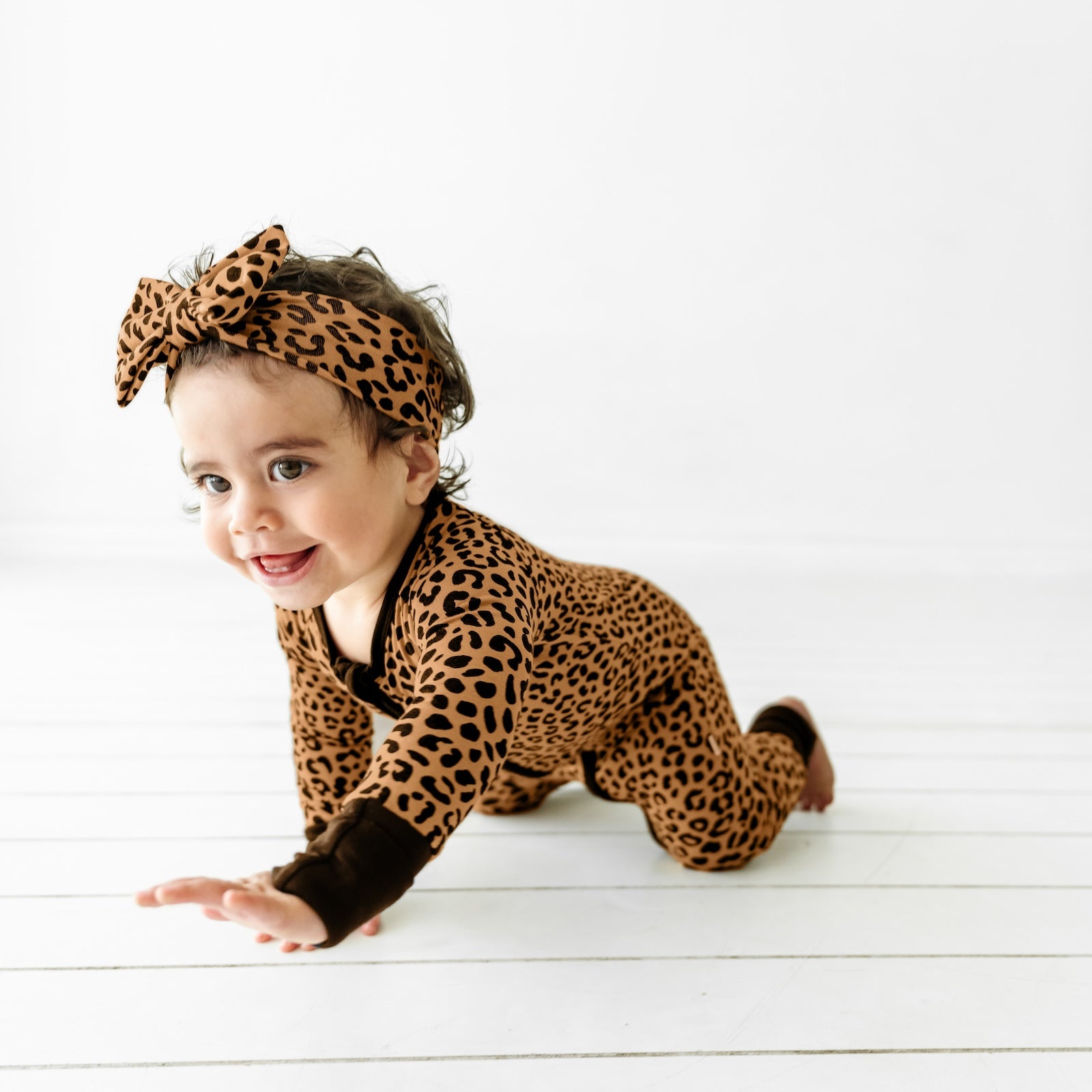 Baby crawling and wearing the Classic Leopard Zippy and Classic Leopard Luxe Bow Headband