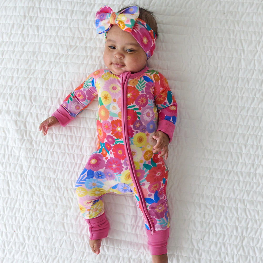 Child laying on a blanket wearing a Rainbow Blooms luxe bow headband and matching zippy