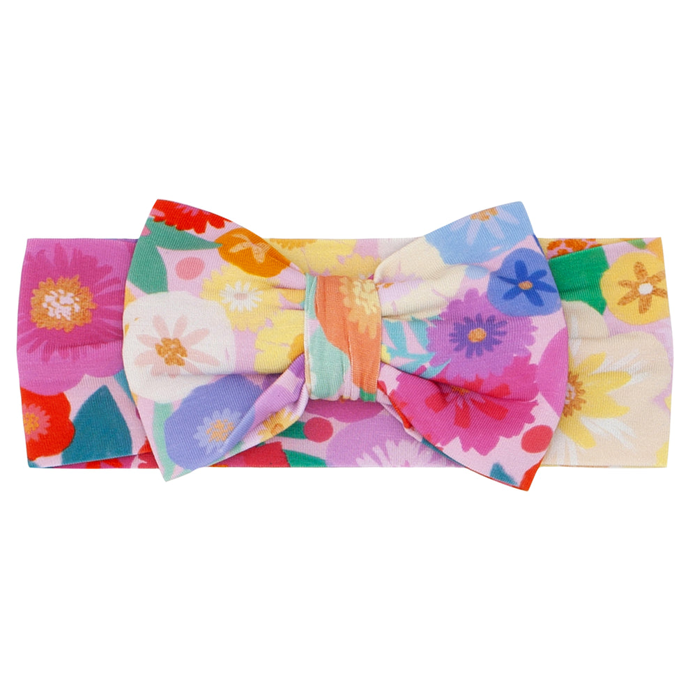 Flat lay image of a Rainbow Blooms luxe bow headband
