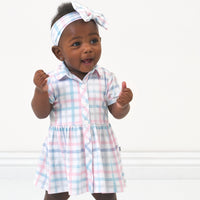 Child wearing a Playful Plaid luxe bow headband and matching dress