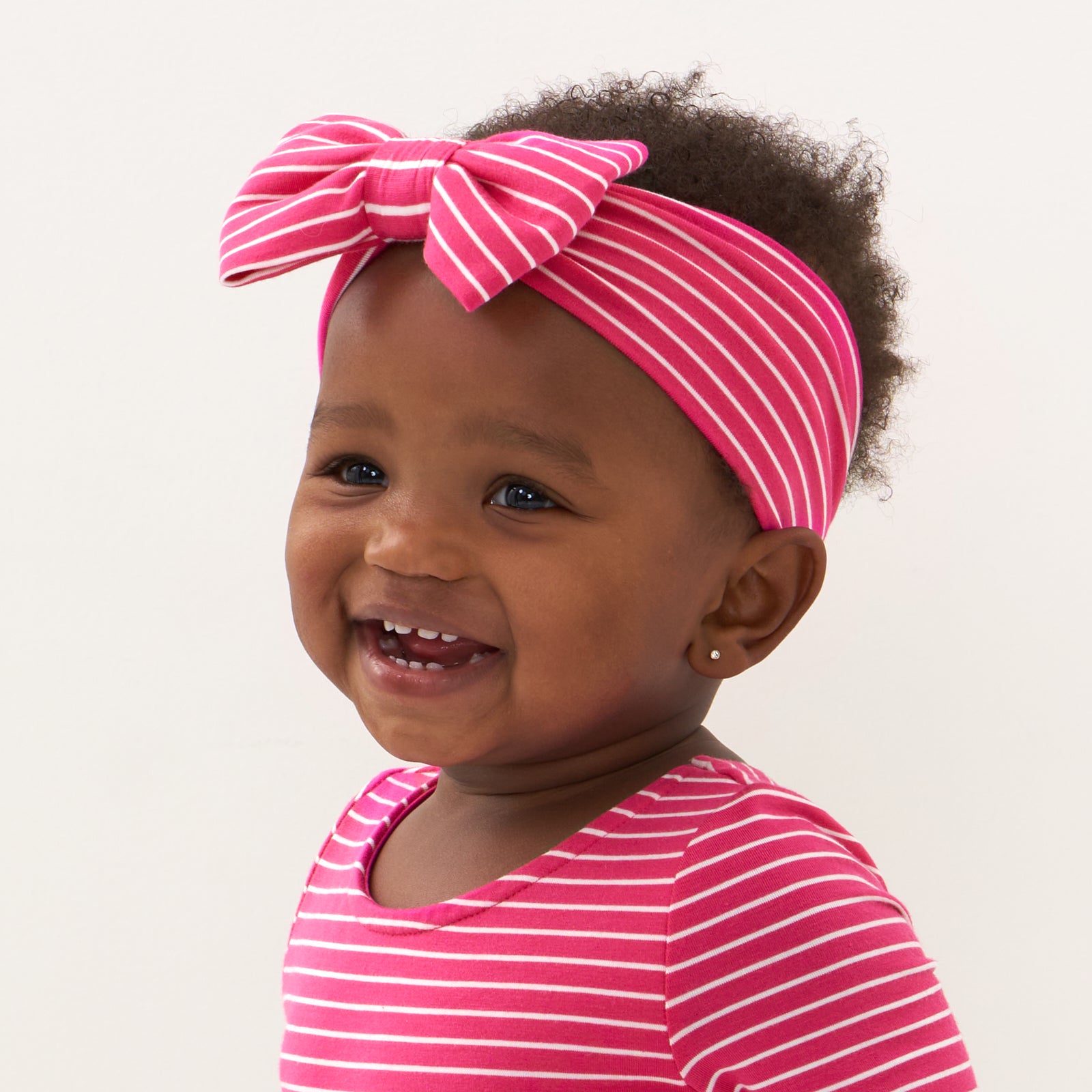 Alternate close up image of a child wearing a Pink Punch Stripes luxe bow headband and matching skater dress