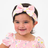 Close up image of a child wearing a Rosy Meadow luxe bow headband and matching dress