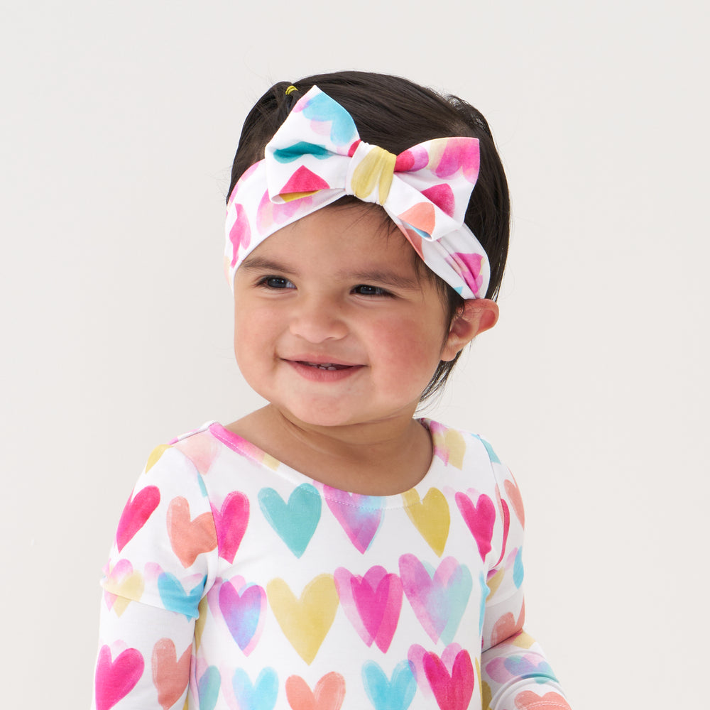 Click to see full screen - Close up image of a child wearing a Watercolor Love luxe bow headband and matching skater dress