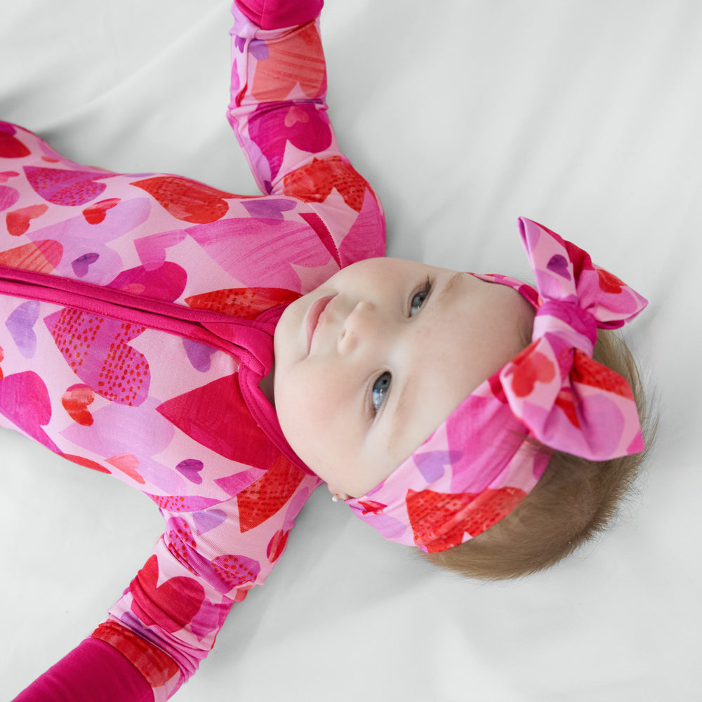 image of a child laying on a bed wearing a Pink Hearts and Crafts Luxe Bow Headband