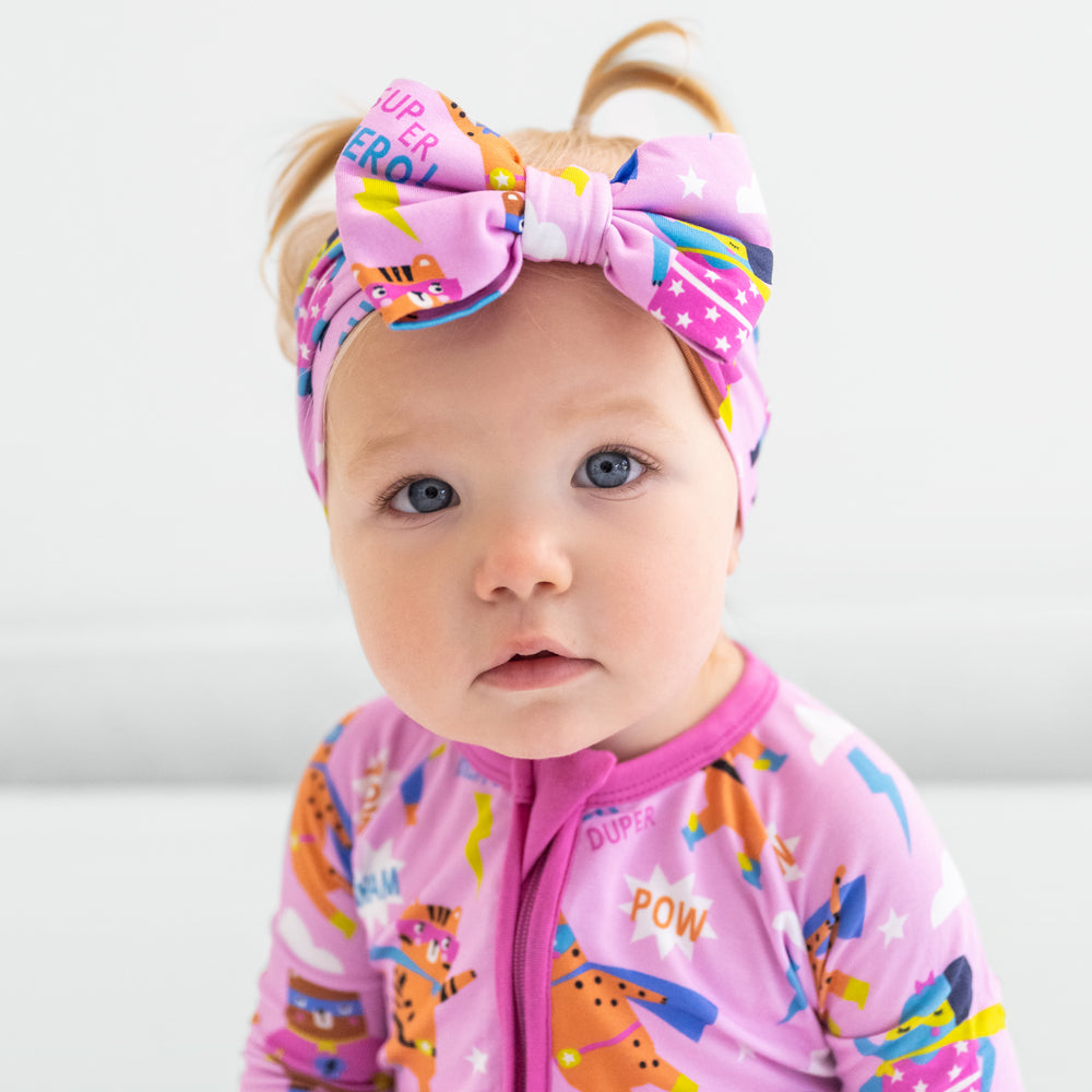 Child wearing a pink Sleepy Heroes zippy with a matching luxe bow headband