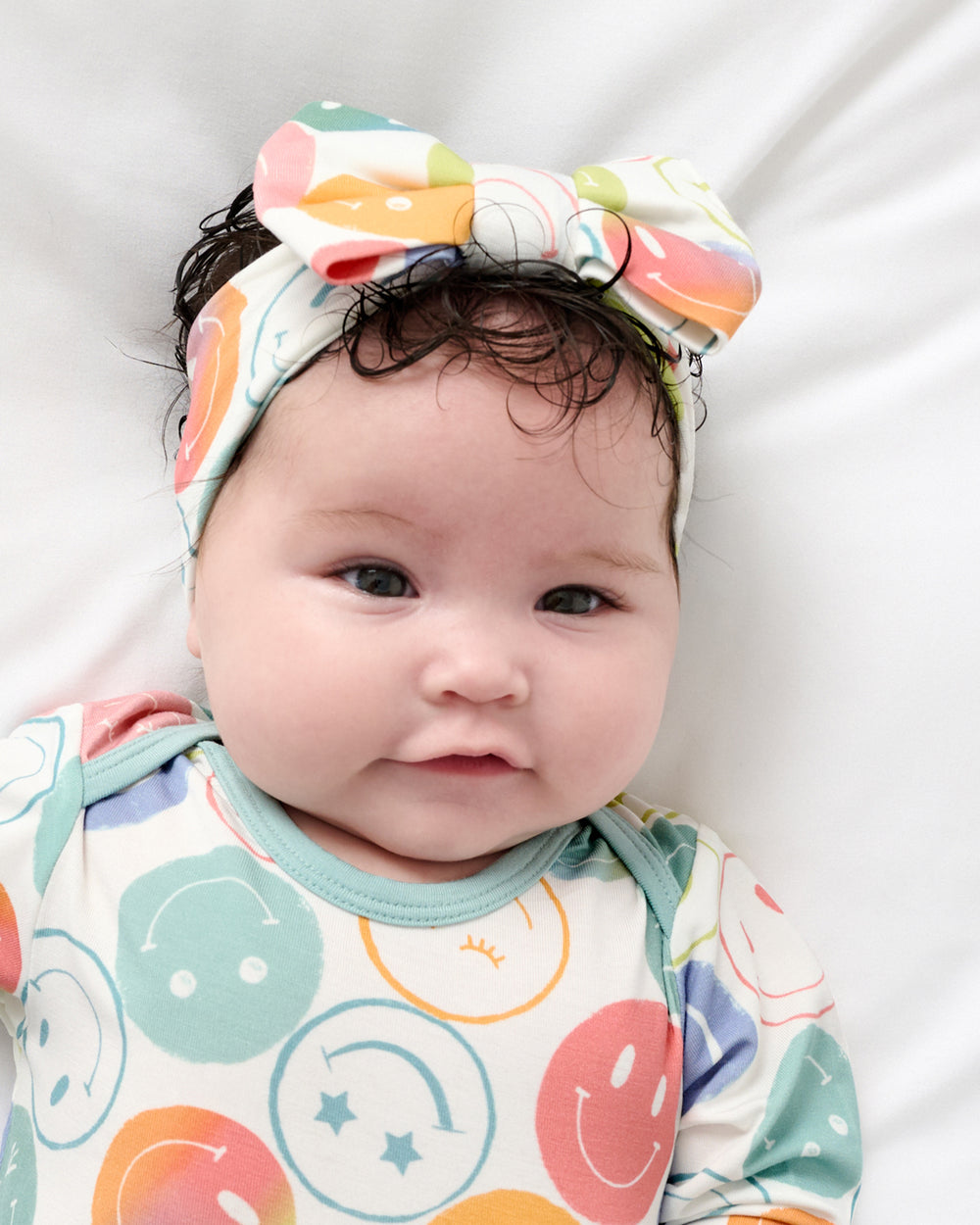 Close up of newborn wearing the Positive Vibes Luxe Bow Headband and Infant Gown