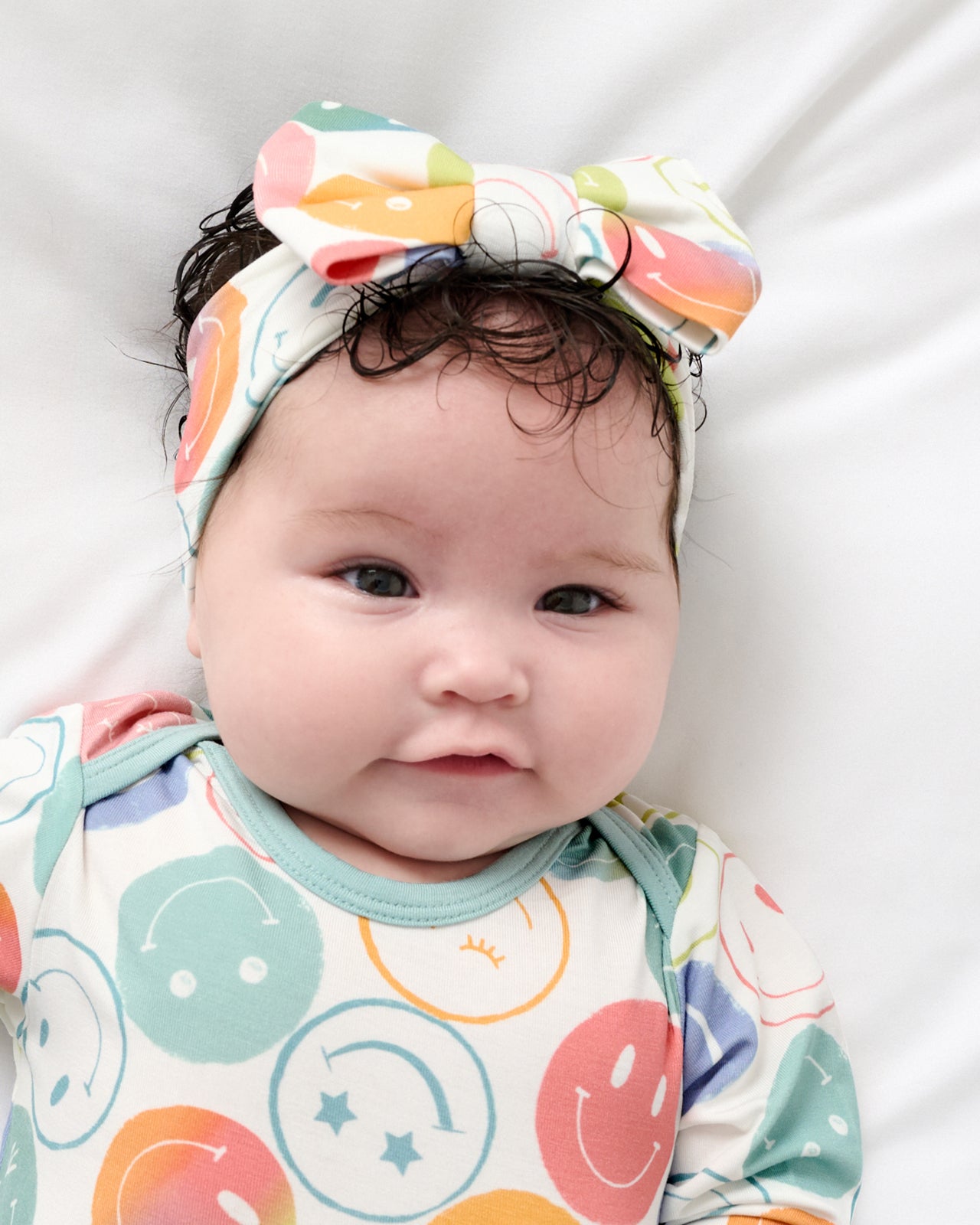Close up of newborn wearing the Positive Vibes Luxe Bow Headband and Infant Gown
