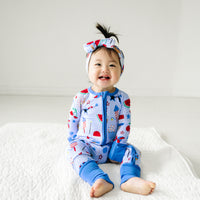 Child wearing a Stars, Stripes, and Sweets zippy paired with a matching luxe bow headband