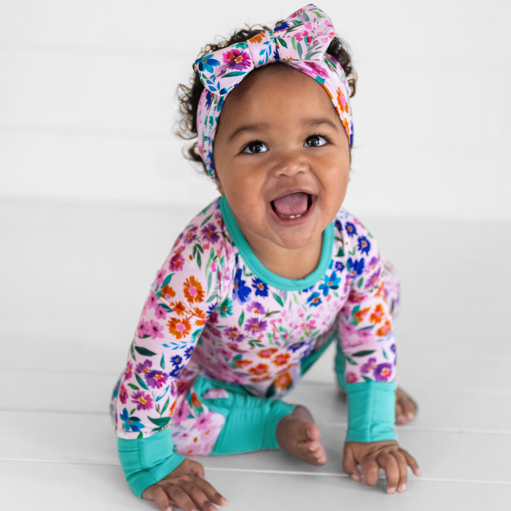 Image of a child wearing a Sweet Pea Floral luxe bow headband and a matching crescent zippy