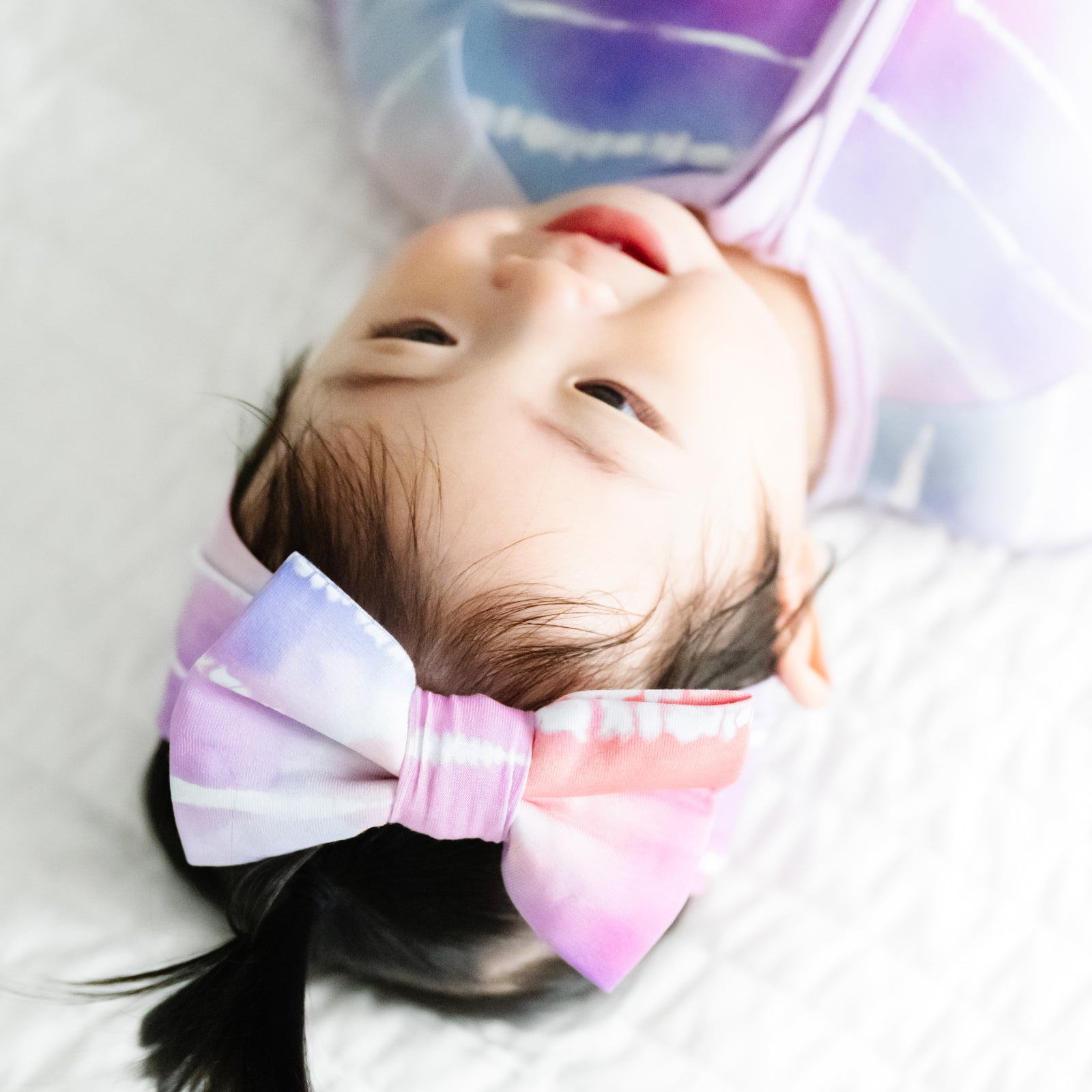 Alternate close up image of a child wearing a Pastel Tie Dye Dreams luxe bow headband and matching zippy